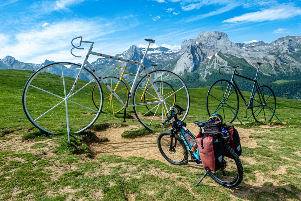 pexels-photo-32742008 Colorful bicycle sculptures with a stunning mountain backdrop under a vibrant blue sky.